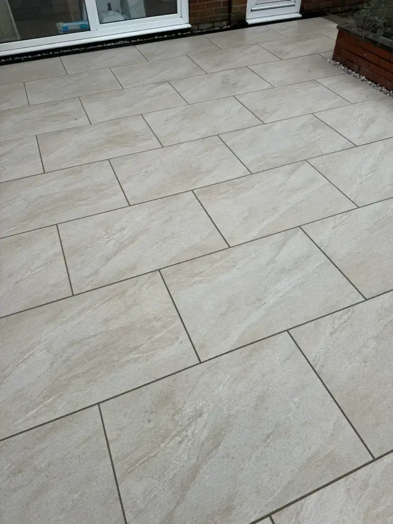 Beige porcelain patio tiles arranged in a clean staggered layout beside a modern villa in Dubai, showcasing a smooth matte finish and precise joint lines — a luxury low-maintenance outdoor flooring installation by Reshape Landscaping Dubai.