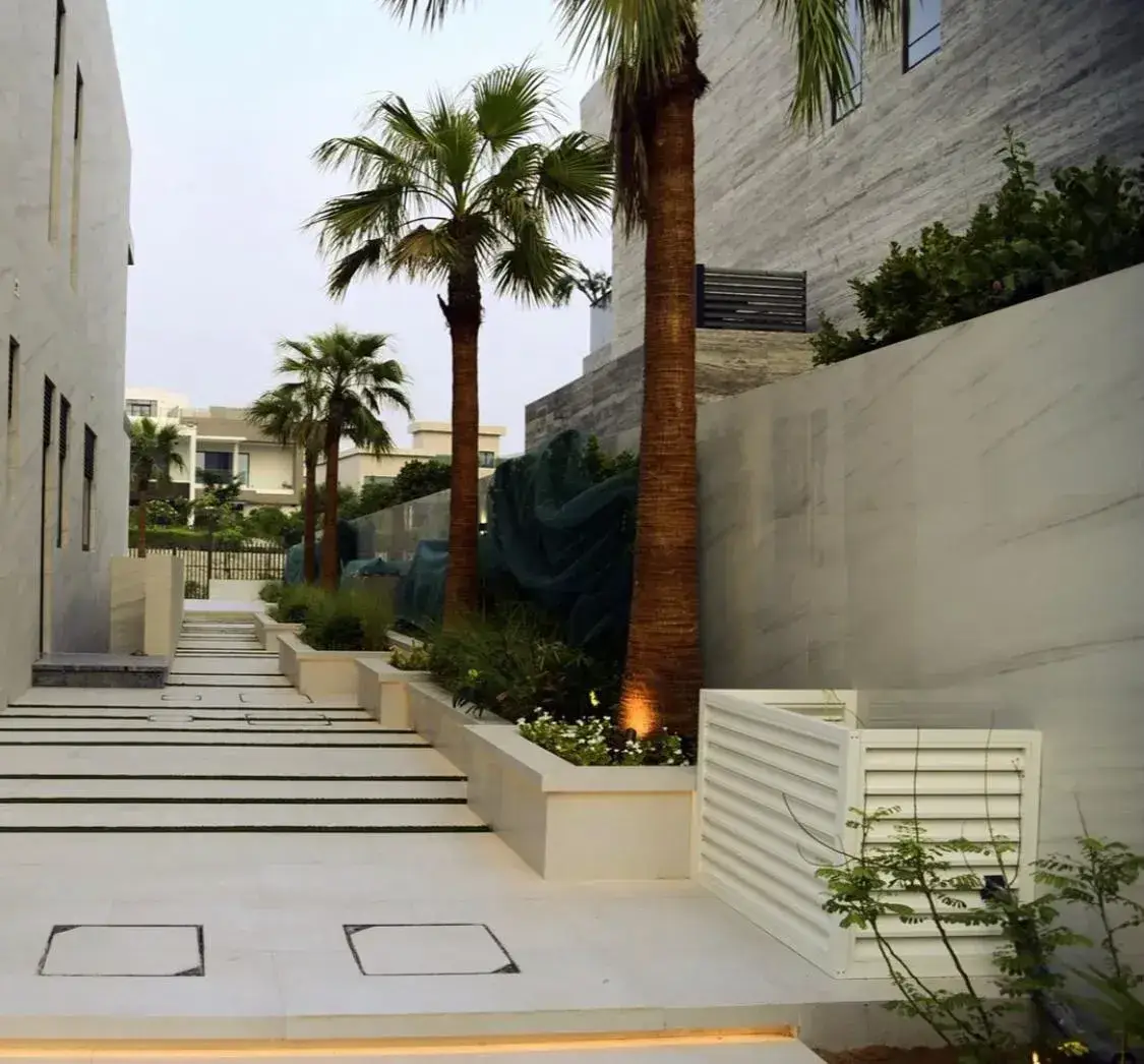 Contemporary villa landscape with palm trees and modern pathway design in Dubai. Created by Reshape Landscaping and Design, a British-owned landscaping company in Dubai specialising in modern villa exteriors, hardscaping, and bespoke garden design.