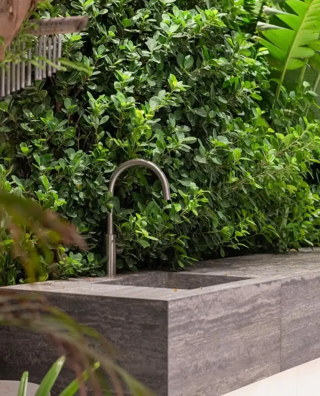 Outdoor stone sink surrounded by lush tropical planting in a luxury Dubai villa garden. Designed and installed by Reshape Landscaping and Design, a British-owned landscaping company in Dubai known for modern outdoor living spaces and bespoke garden features.